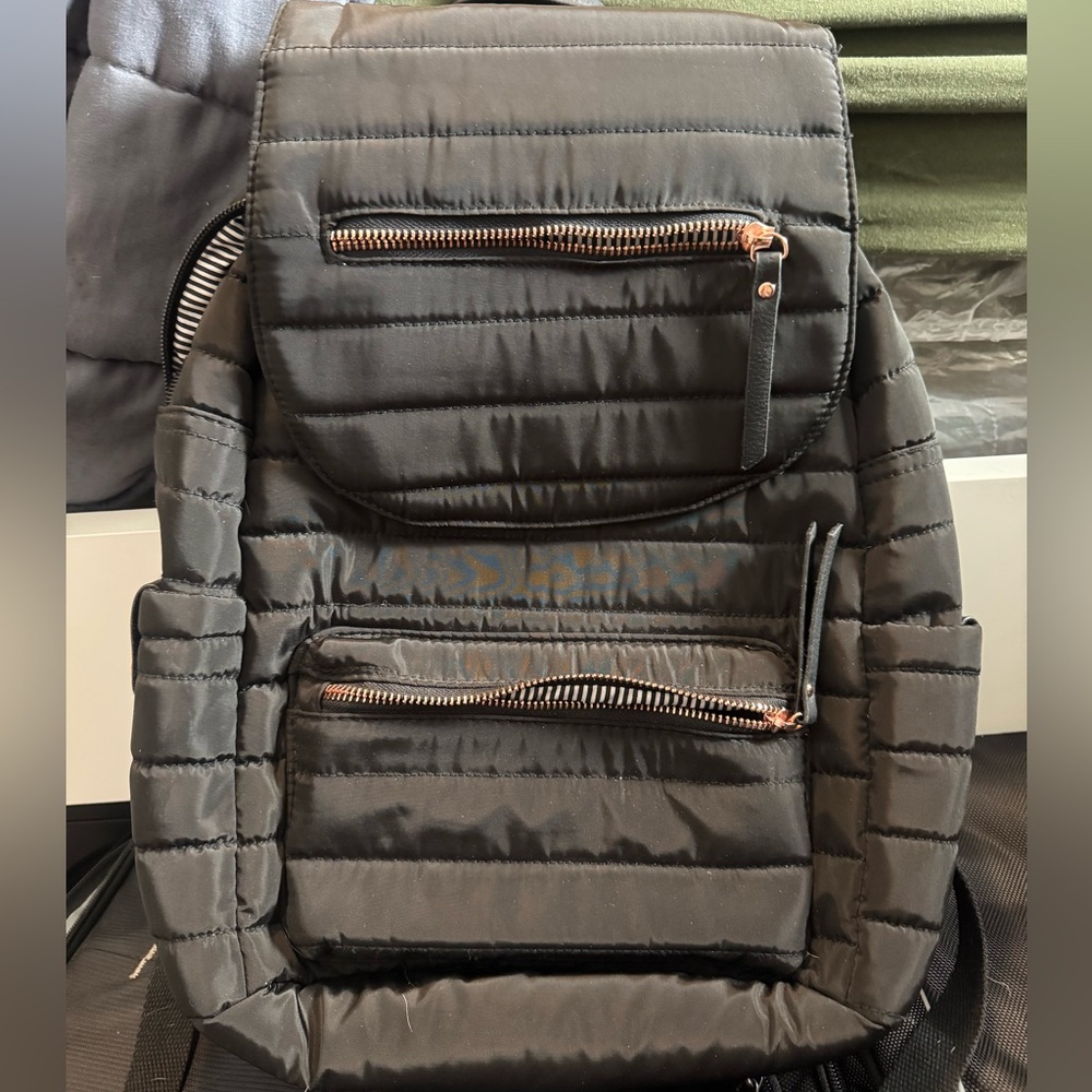 Black backpack with pinkish gold zippers